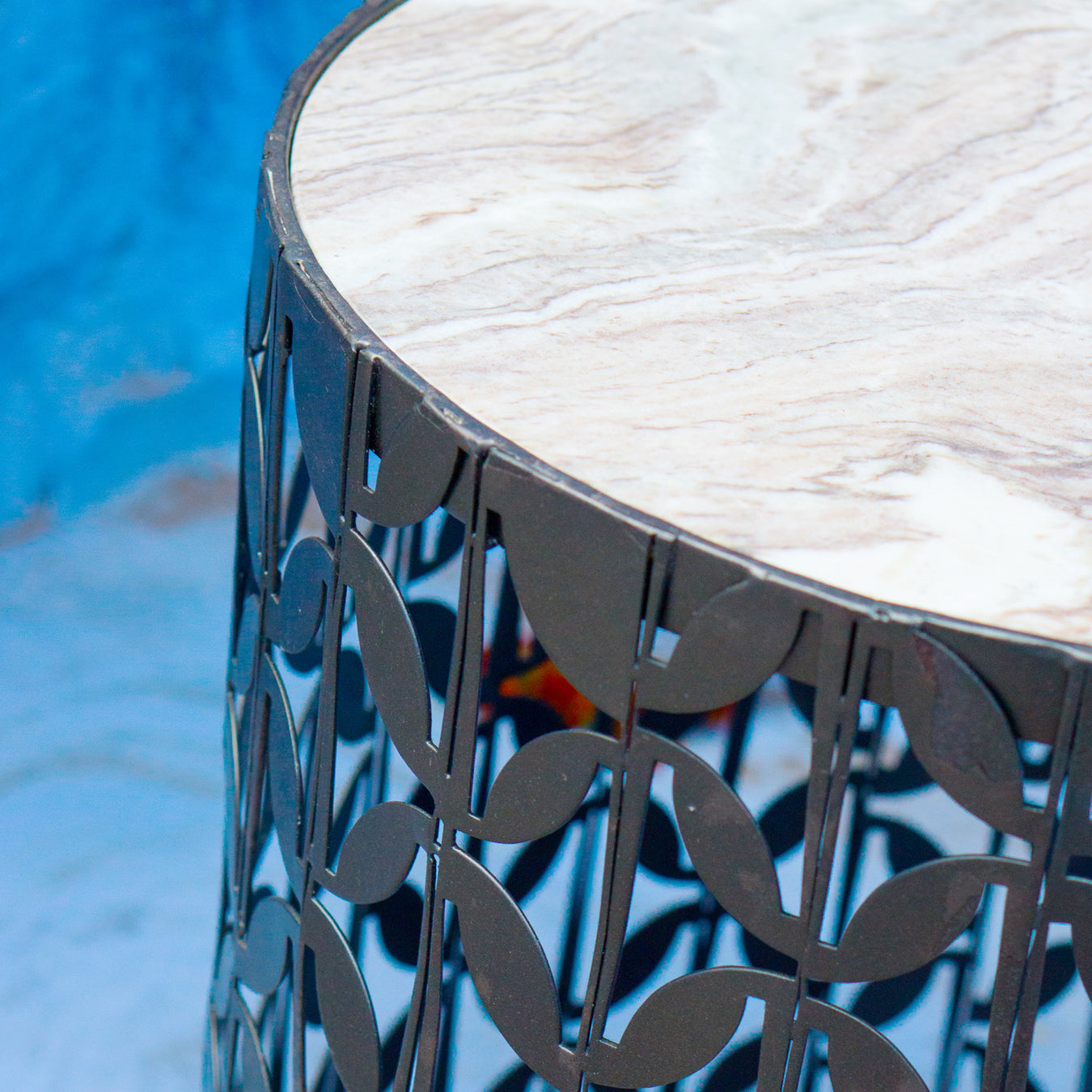 Close up of metal Gianna table against blue background.