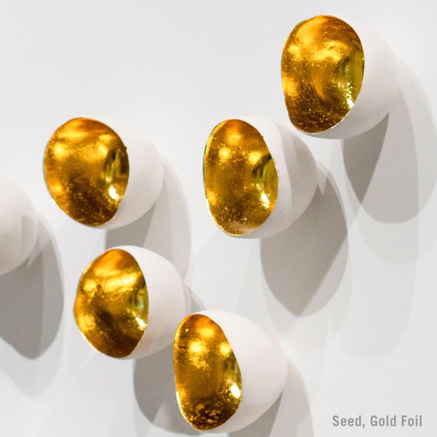 Gold foil-covered seeds on a white background