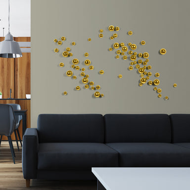 Gold spherical wall art on a gray wall above a black sofa in a living room.