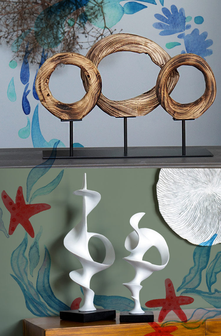 Two images with ocean graphic overlay. Image on top shows a sculpture of three wood rings on an iron stand. The bottom image shows two curvilinear white sculptures.