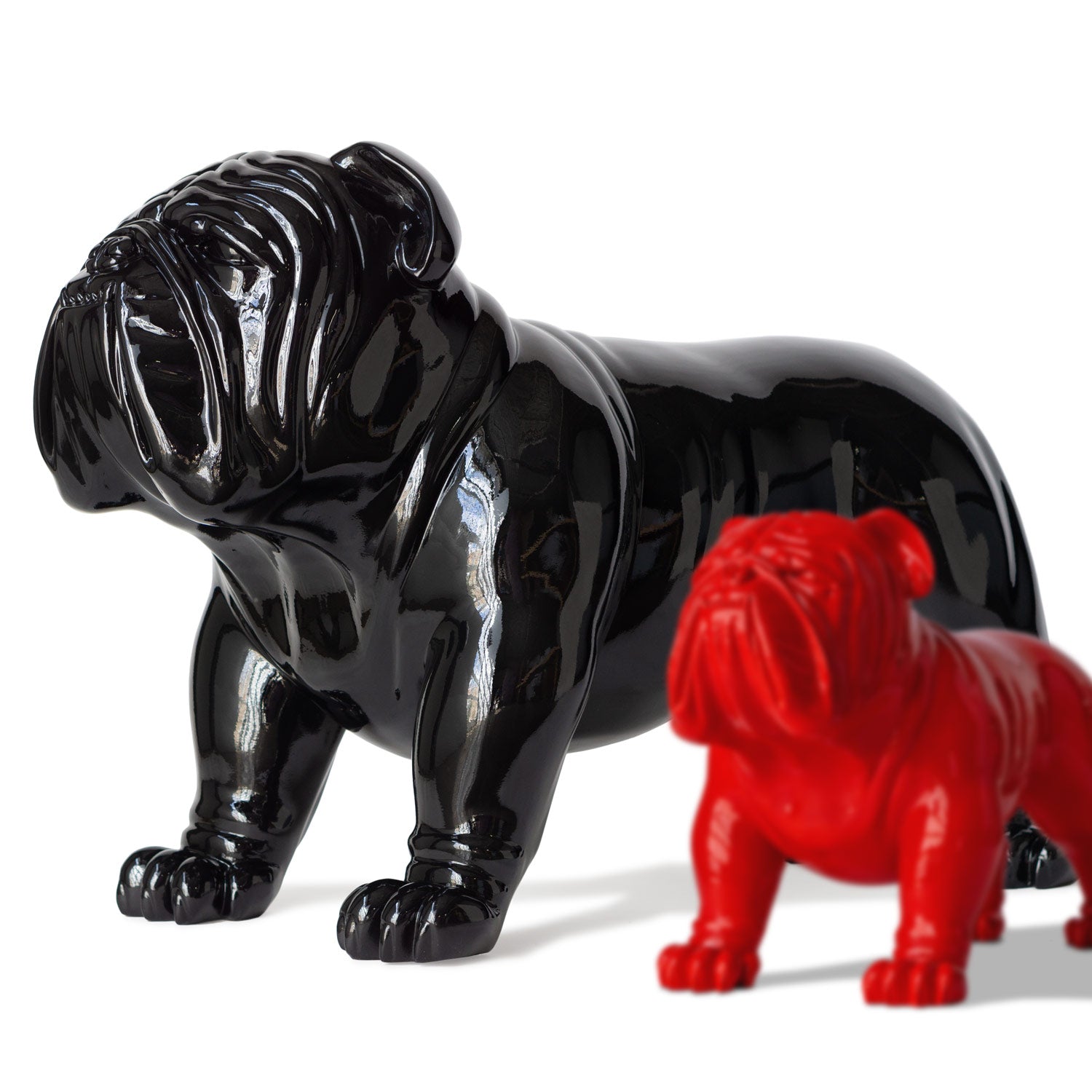 Large glossy black bulldog sculpture next to a smaller red bulldog sculpture on a white background.