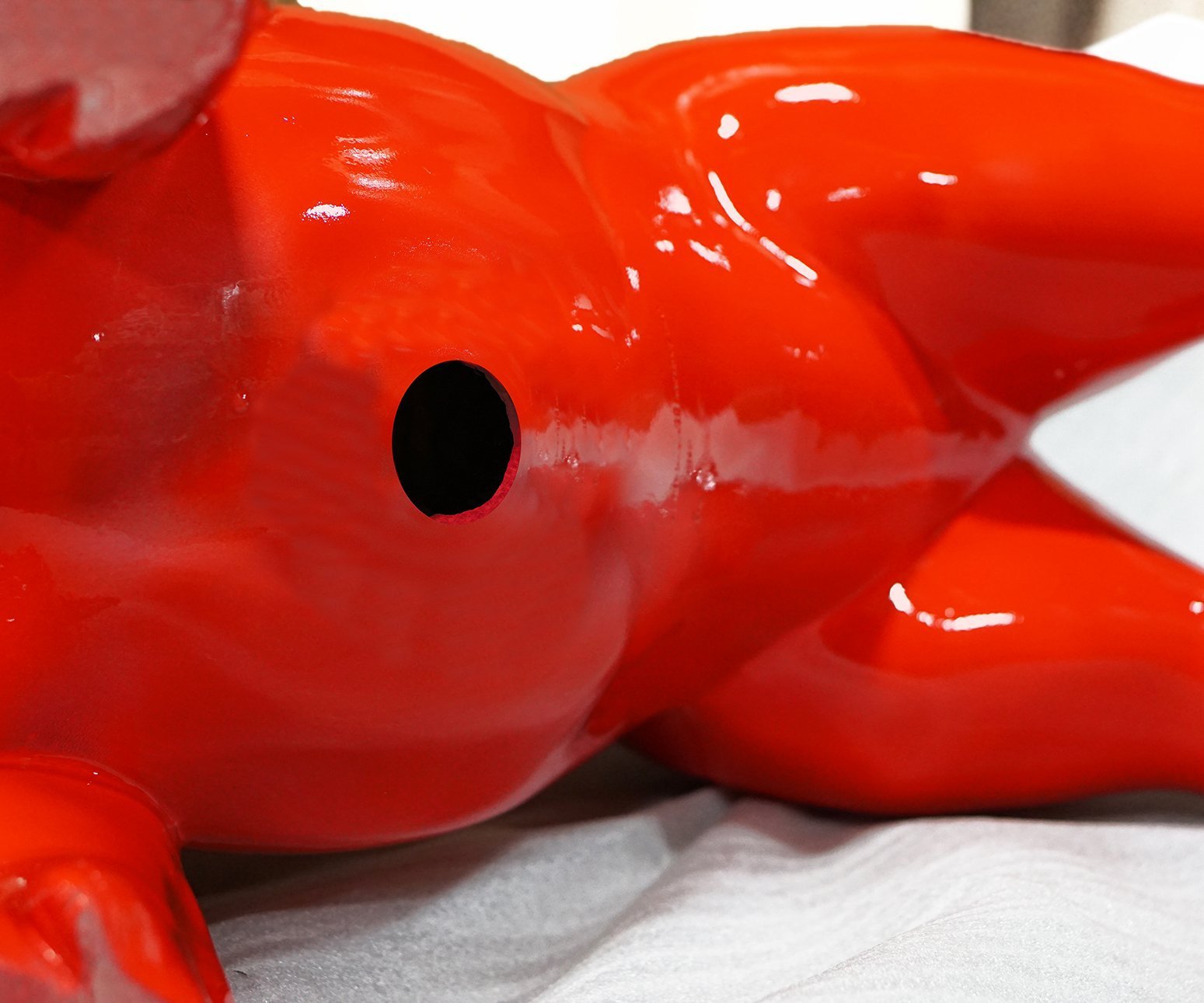 Underside of a red large fiberglass bulldog sculpture showing a hole in the belly.